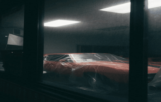 black car parked inside a modern garage with ambient lighting.