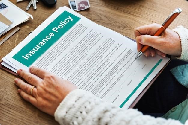 Person reviewing and signing an insurance policy document at a desk.