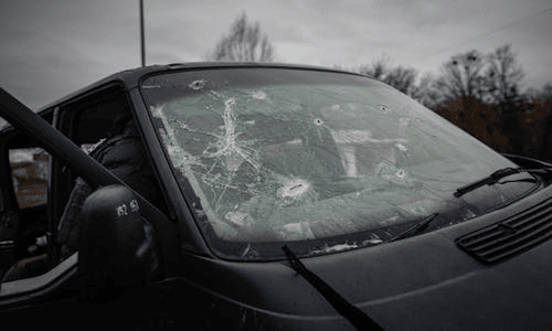 Car with a shattered windshield showing extensive glass breakage and cracks.